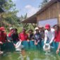 Kepala desa Banjarsari ( baju putih topi merah) sedang menabur benih ikan nila pada sistem pengairan bioflox.(Dok.Apakabarbogor/wan).